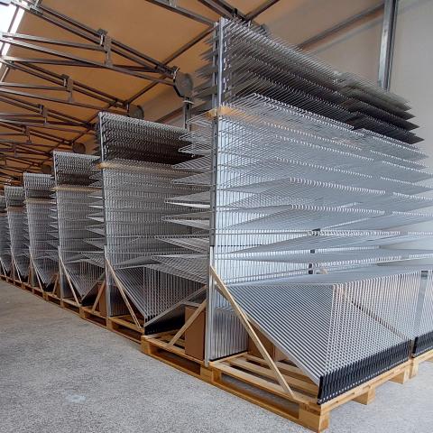 A picture of rows of SKA-Low antennas. Each row has tens of antenna-structures. The structures look like flat iron Christmas trees with smaller arms on top growing longer towards the bottom. 